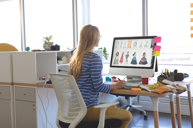 Diseñadora de moda que usa una tableta gráfica mientras trabaja en su escritorio