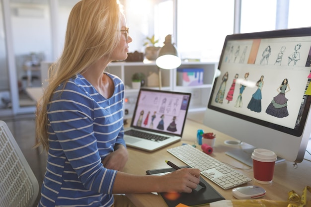 Diseñadora de moda que usa una tableta gráfica mientras trabaja en su escritorio