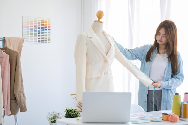 Diseñadora de moda trabajando en estudio, cortando dibujos, cosiendo vestidos