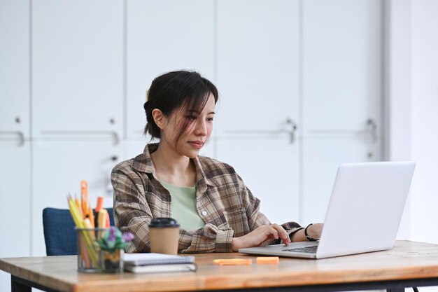 Diseñadora que trabaja con una computadora portátil en un lugar de trabajo creativo