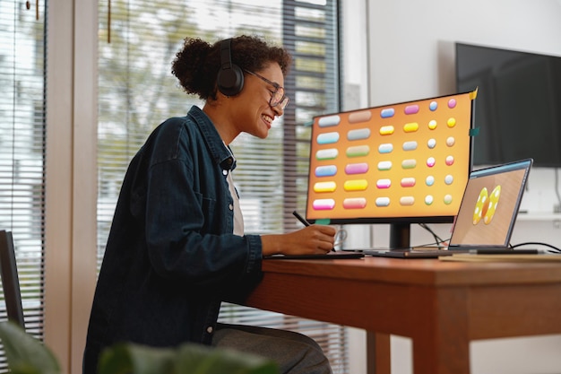 La diseñadora trabaja en la oficina en casa dibujando en una tableta gráfica independiente que trabaja en un proyecto