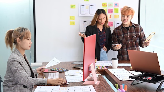 Los diseñadores de la experiencia del usuario están haciendo una lluvia de ideas y planificando juntos el diseño del marco del prototipo del boceto del futuro proyecto de diseño de la aplicación