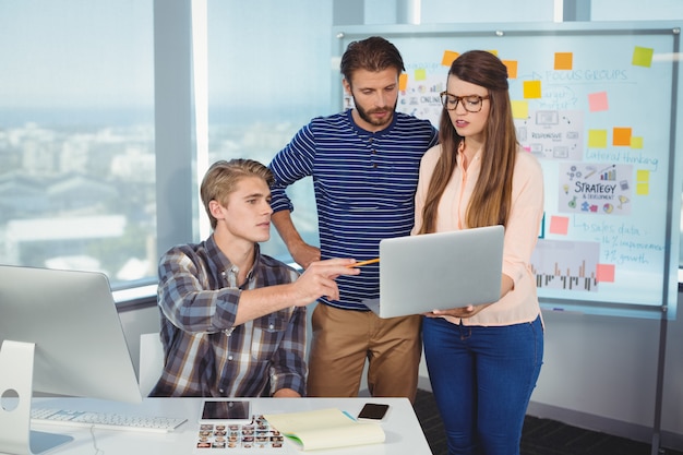 Foto diseñadores gráficos discutiendo sobre laptop