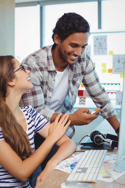 Diseñadores gráficos masculinos y femeninos que interactúan entre sí en el escritorio