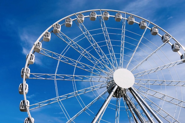 Diseñe en metal una noria o una atracción con cabañas para una revisión panorámica contra el cielo azul