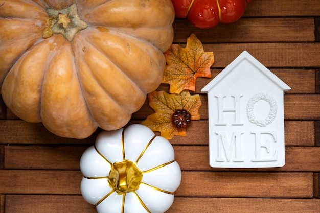 Diseño acogedor sobre un fondo de madera de listones con calabazas, hojas de otoño, una casa y llaves, humor otoñal, seguro hipotecario de reubicación de viviendas de Halloween