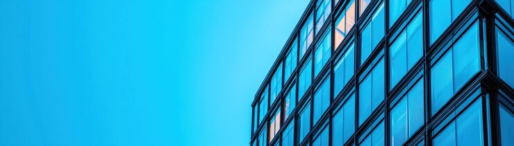Diseño arquitectónico moderno con edificios de vidrio contra un cielo azul brillante que muestra líneas elegantes y superficies reflectantes que evocan un sentido de innovación y elegancia
