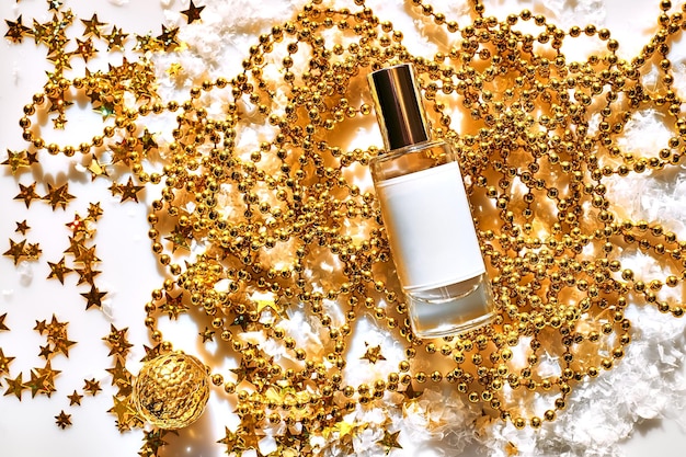 Diseño de botella de vidrio de perfume en blanco sobre fondo dorado brillante con confeti de brillo holográfico en forma de estrellas Maqueta de producto de belleza cosmética del paquete