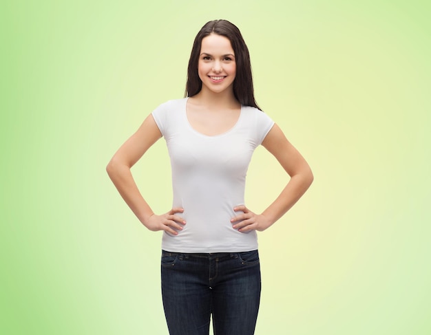 Diseño de camisetas y concepto de personas: joven sonriente con una camiseta blanca en blanco sobre fondo natural verde