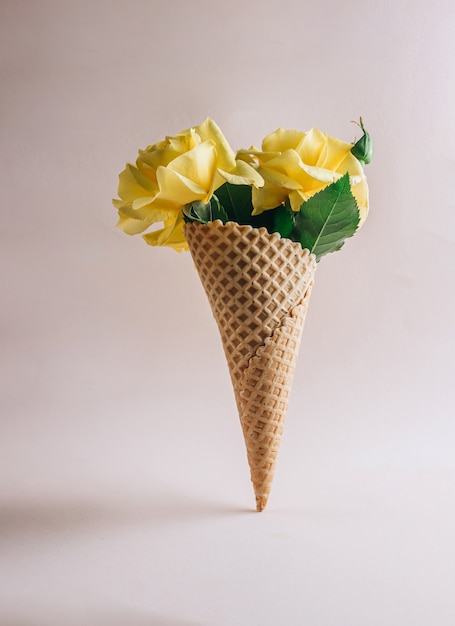 Diseño creativo y composición de cono de galleta y rosas amarillas sobre fondo beige. Levitación