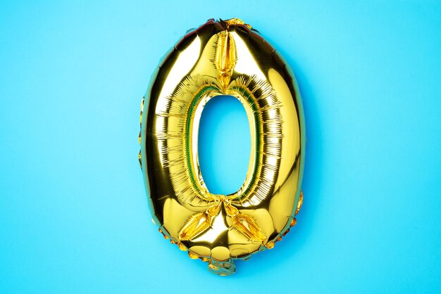 Diseño creativo Globo de lámina dorada número cero 0 Tarjeta de felicitación de cumpleaños Concepto de aniversario Vista superior Espacio de copia Elegante letra dorada O sobre fondo azul Dígito cero