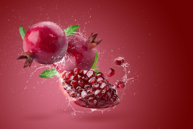 Diseño creativo hecho de fruta de granada fresca y agua salpicada de fondo rojo