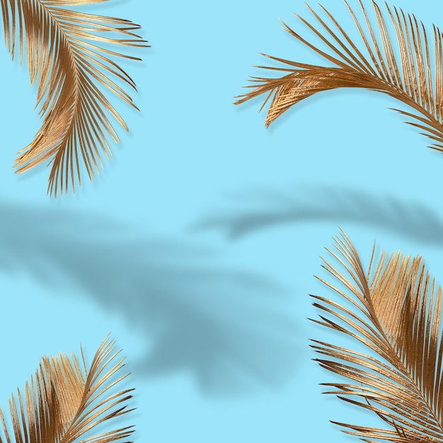 Diseño creativo hecho de hojas de palmeras tropicales doradas sobre un fondo verde claro Minimal Summer Quit
