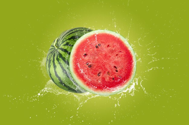 Diseño creativo hecho de sandía y agua salpicando sobre un fondo verde