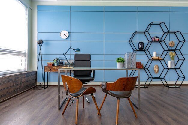 Diseño creativo moderno y moderno de una oficina de estudio personal en el estilo del minimalismo en colores azul y beige con grandes ventanales y luz natural.