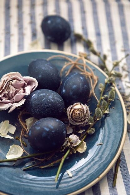 Diseño de decoración huevos de pascua azules yacen en un plato con un sauce sobre un fondo de tela a rayas