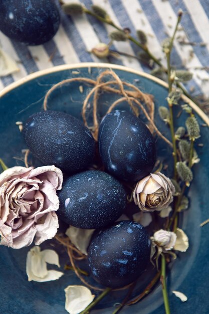 Diseño de decoración huevos de pascua azules yacen en un plato con un sauce sobre un fondo de tela a rayas