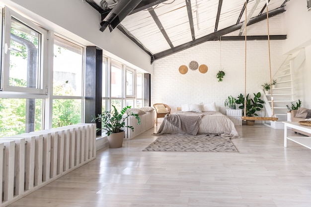Diseño de dormitorio de lujo en una cabaña rústica de estilo minimalista. paredes blancas, ventanas panorámicas, elementos de decoración de madera en el techo, columpios de cuerda en medio de una habitación espaciosa.