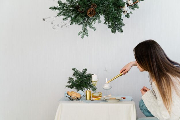 Diseño estético para navidad con guirnalda colgante de pino nobilis, velas y adornos de mesa.