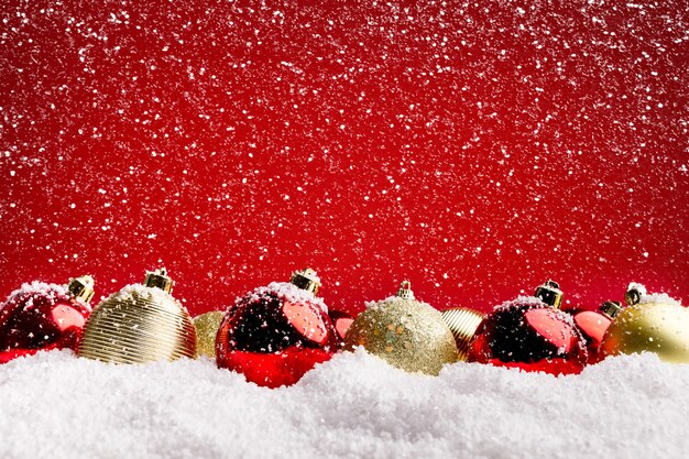 Diseño y fondo de la tarjeta de felicitación de Navidad. Adornos rojos y plateados en la nieve sobre fondo rojo, espacio de copia