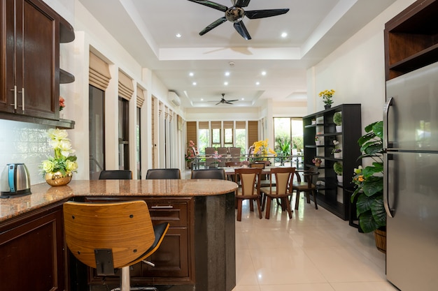 El diseño interior de la casa, hogar, villa y apartamento cuenta con refrigerador, taburete, mostrador de cocina, ventilador de techo, estante y mesa de comedor