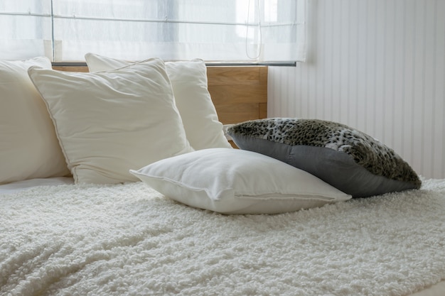 Diseño interior del dormitorio con estilo con las almohadas blancas y negras en cama.