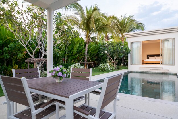 Diseño interior y exterior de mesa de comedor al aire libre junto a la terraza de la piscina de la villa, casa y hogar