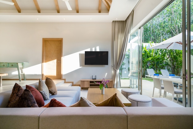 Diseño interior y exterior de sala de estar con vista a la piscina en villa de lujo con piscina