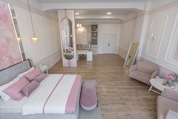 Foto diseño interior moderno y acogedor de una habitación con un dormitorio y una oficina en casa en cálidos y delicados colores rosa pastel y beige