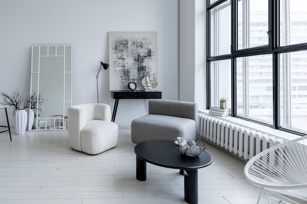 Diseño interior moderno y minimalista de habitación monocromática clara y luminosa con muebles en blanco y negro, paredes blancas limpias y ventanas enormes