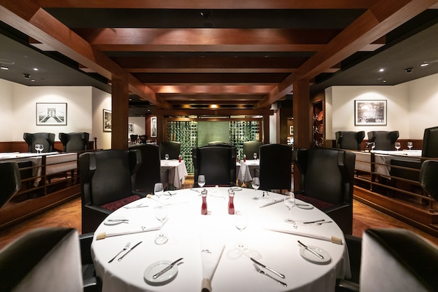 Diseño interior del restaurante Steak House con muebles de lujo contemporáneos en estilo neoyorquino, elegantes sillas de cuero negro. Deluxe, espacioso y confortable lugar de alta cocina.