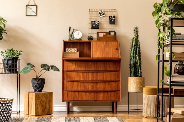 Diseño interior retro de sala de estar con escritorio vintage de madera, estante, puf dorado, cubo, plantas, cactus, libros.