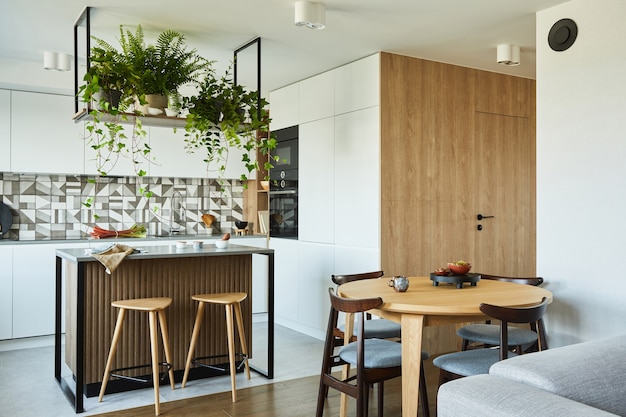 Diseño de interiores de cocina elegante con comedor. Espacio de trabajo con accesorios de cocina en la parte trasera. Paredes creativas con paneles de madera. Estilo minimalista un concepto de amor a las plantas.