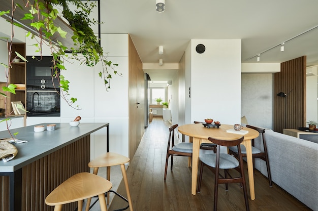 Diseño de interiores de cocina elegante con comedor. Espacio de trabajo con accesorios de cocina en la parte trasera. Paredes creativas con paneles de madera. Estilo minimalista un concepto de amor a las plantas.