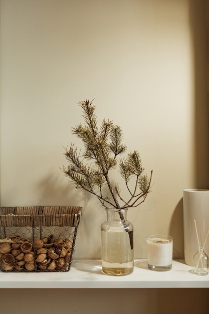 Diseño de interiores de cocina minimalista decorado con rama de abeto en florero de vidrio, canasta de nueces, velas, palos aromáticos