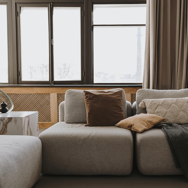 Diseño de interiores escandinavo moderno y estético Elegante salón bohemio con cómodos sofás, almohadas, ventanas, cortinas, mesa auxiliar de mármol a cuadros