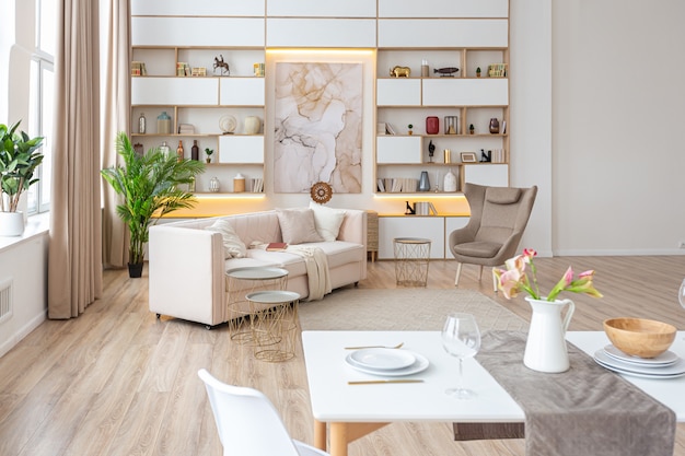 Diseño de interiores espacioso apartamento luminoso en estilo escandinavo y cálidos colores blanco pastel y beige. muebles de moda en la sala de estar y detalles modernos en el área de la cocina.