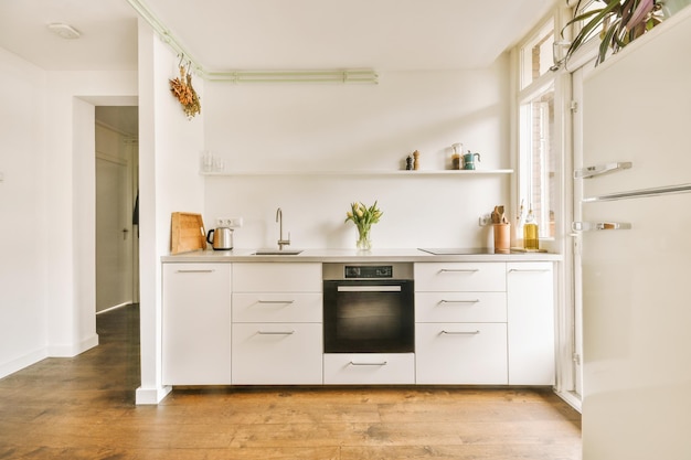 Foto diseño de interiores de espacioso estudio con ventanas y suelo laminado y paredes blancas amuebladas con juego de cocina