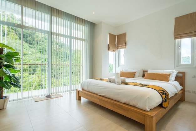 Diseño de interiores de lujo en el dormitorio de la villa de la piscina con cama de matrimonio acogedor.