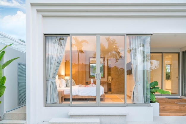 Diseño de interiores de lujo en el dormitorio de la villa de la piscina con techos altos y rosas en la cama en la casa o edificio de la casa