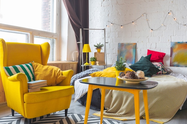 Diseño de interiores de lujo de moda en estilo escandinavo de apartamento estudio con muebles de color amarillo brillante y decorado con luces