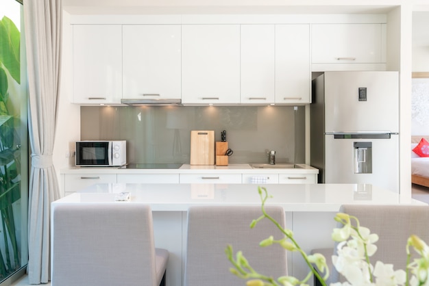 Diseño de interiores de lujo en salón de villas de piscina. Amplio y luminoso espacio con techos altos y área de cocina con mesa de comedor.