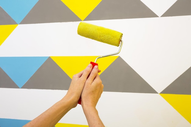 Diseño de interiores. La niña pinta la pared de amarillo. rodillo y bandeja de pintura.