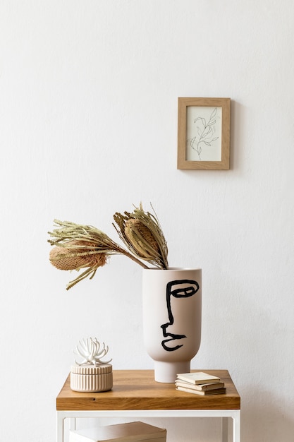 Foto diseño de interiores de sala de estar con elegantes flores secas en jarrón, mesa de centro de madera, marco de póster, decoración y accesorios personales en la decoración del hogar moderno.