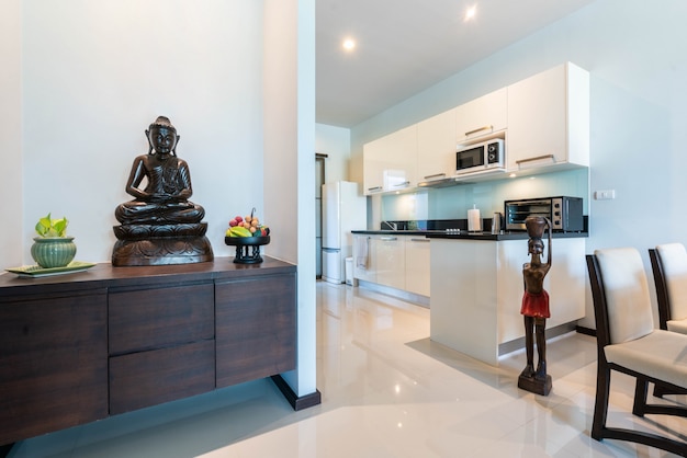 Diseño de interiores totalmente amueblado villa equipada con cocina, mesa de comedor y decoración de Buda