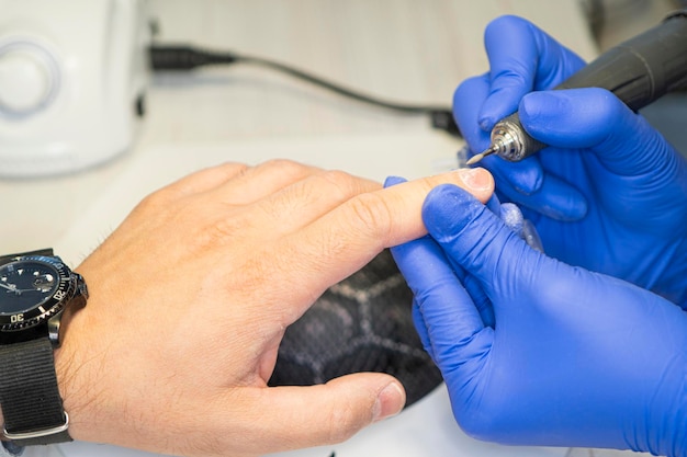 Diseño de manicura masculina El maestro hace la manicura de un hombre El concepto de cuidado profesional de las uñas Primer plano de las manos del manicurista en el trabajo Un hombre hace una manicura Manicura masculina