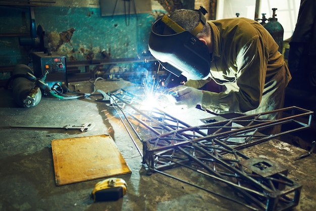 Diseño de metal de soldadura de soldador de una grúa de construcción sobre la mesa de hierro