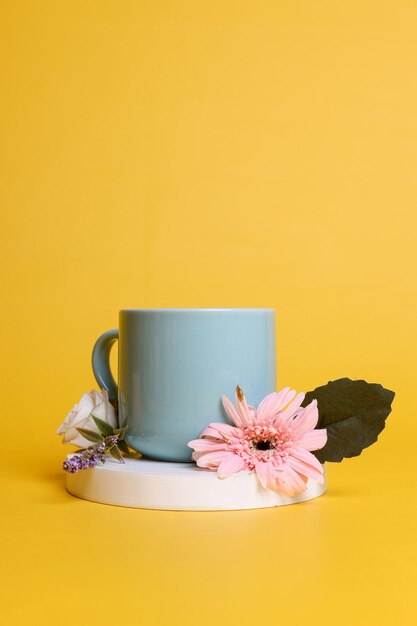 Diseño minimalista de copa verde sobre podio redondo blanco decorado con flores y hojas Taza o taza para