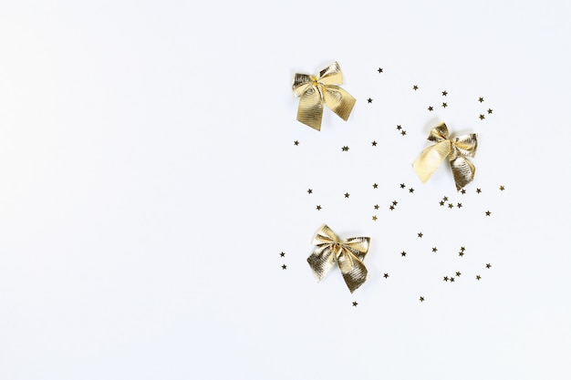 Diseño de navidad Confeti dorado en forma de estrellas y lazos sobre un fondo blanco.
