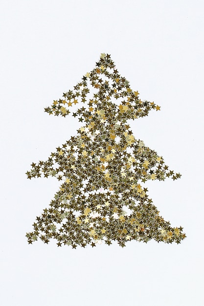 Diseño navideño. Confeti dorado en forma de estrellas dobladas en forma de árbol de Navidad